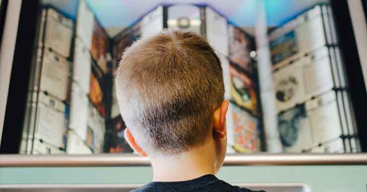 Young boy looking at a shelf with lots of options to choose from pictures. 