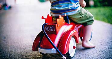 Young child riding a toy fire truck.