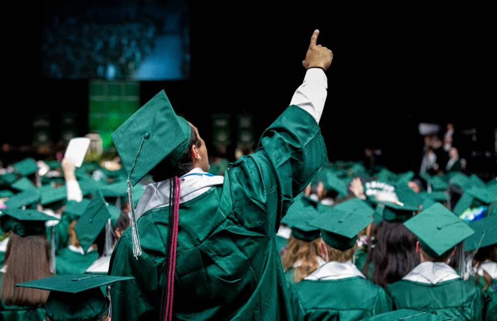 Student pointing towards the ceiling during a graduation ceremony