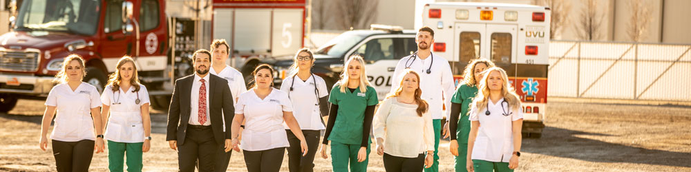 A group of medial professionals walking towards camera with emergency medical vehicles in the background