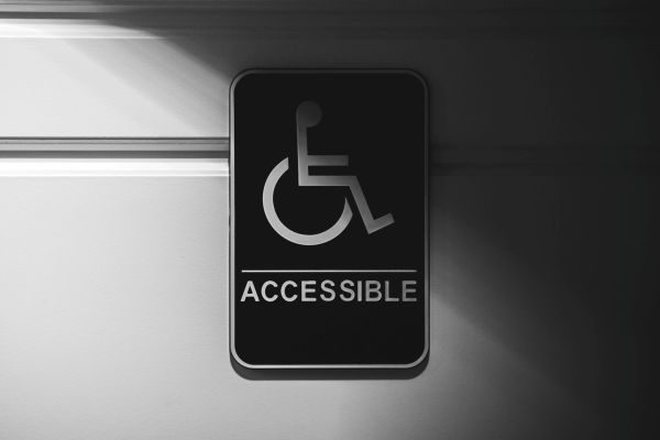 Black and white sign with a wheelchair user and the word accessible under it.