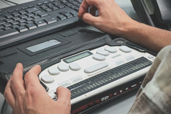 Person using a Braille Keyboard connected to a normal keyboard