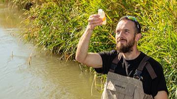 student testing water in lake