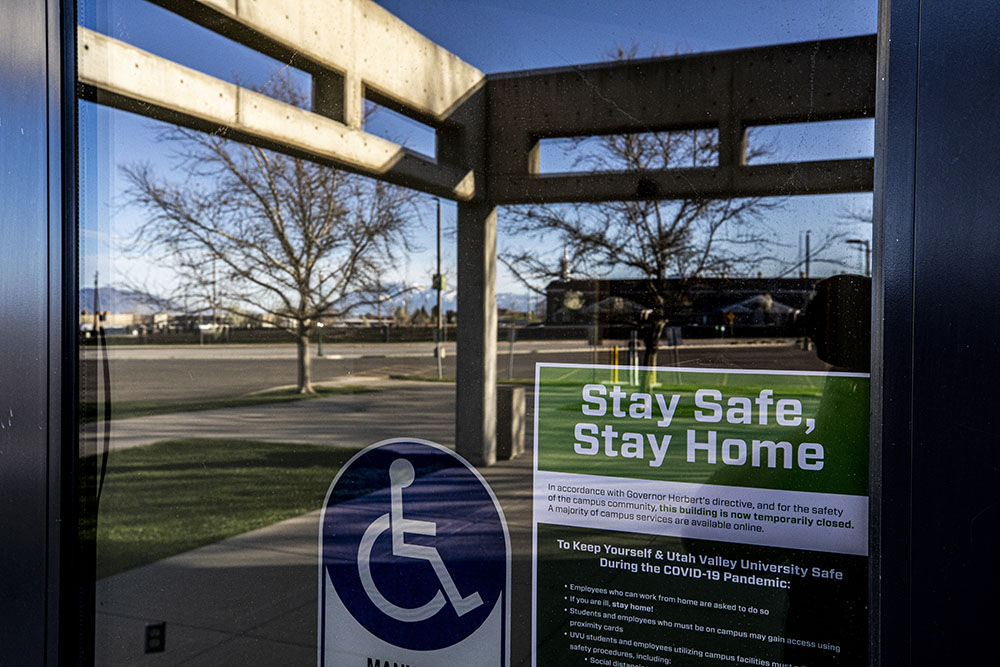 The doors of campus have a sign telling visitors "Stay Safe, Stay Home" with details about the virus affecting campus closures