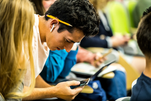 Man sitting in auditorium looking at his phone