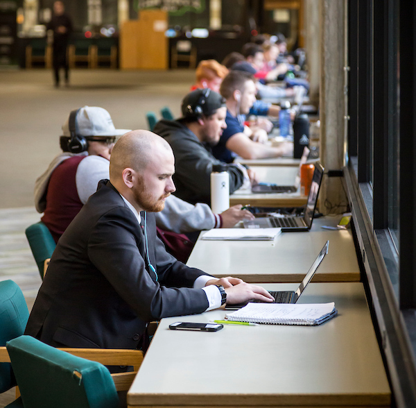 people sitting at tables studying in a hallway