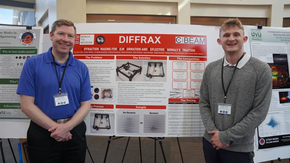 Carter Wilkes poses with professor Vern Hart in front of the DIFFRAX project board