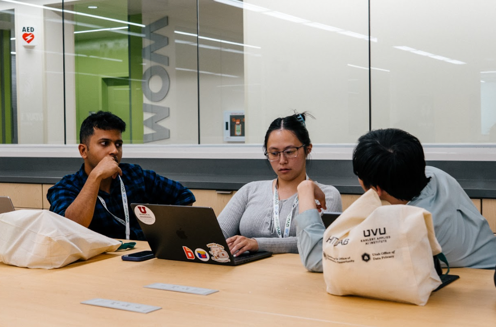 Three students participating in the Hackathon typing on laptops