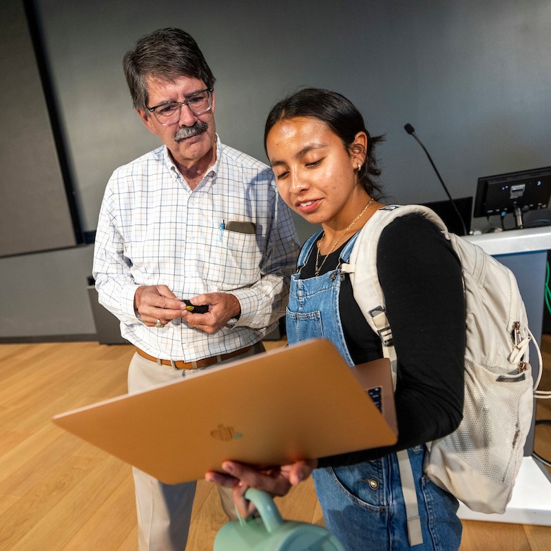 student and professor looking at a laptop together