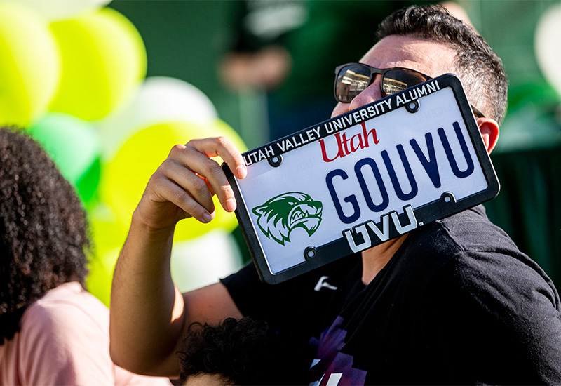 student holding uvu license plate