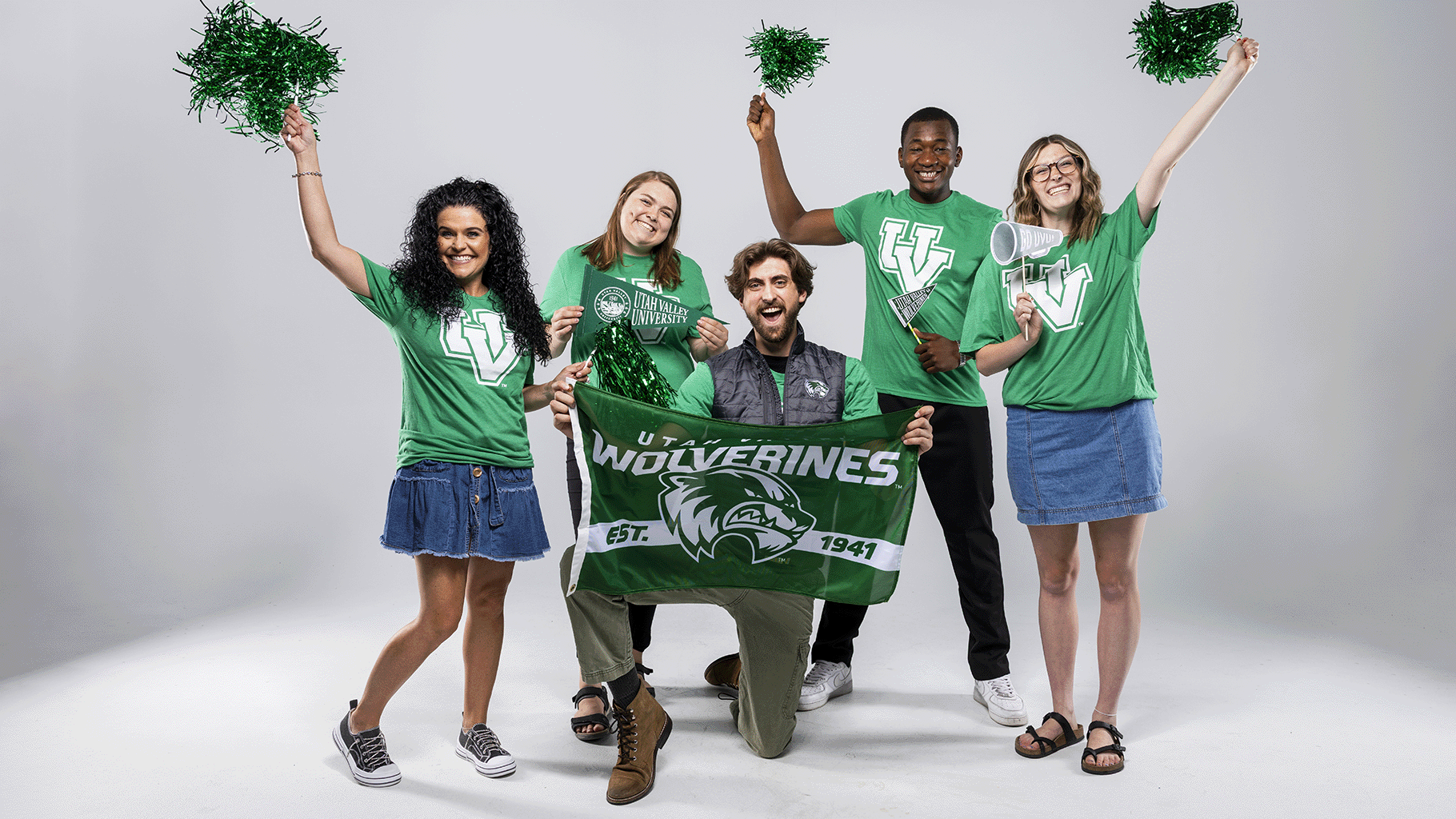 2025-26 Student Alumni Ambassadors smile and post with a UVU flag and pompoms.