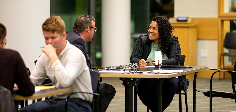 An older man mentors a female student at a table