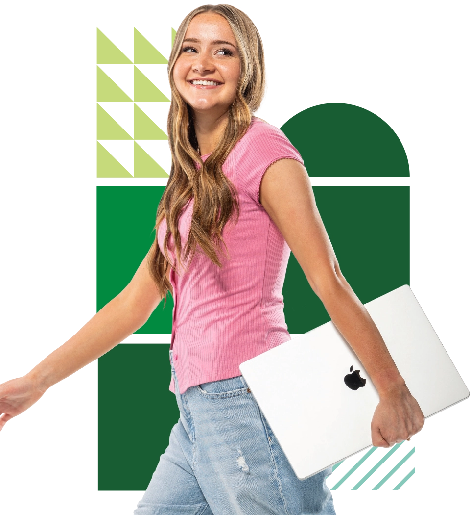 A UVU student with blonde hair, wearing a pink top and jeans, smiles and holds a laptop. 