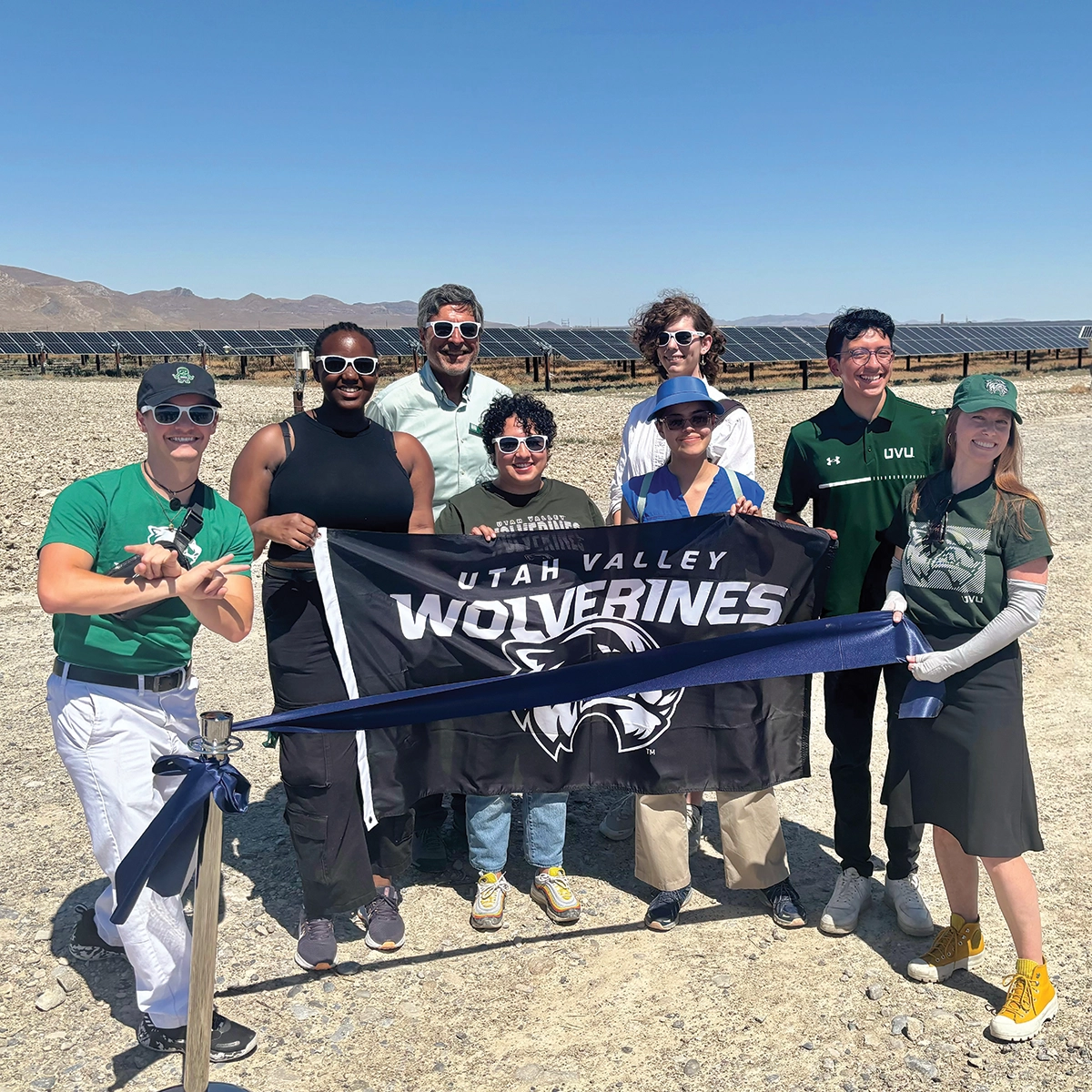 Students and faculty from the UVU College of Science pose in front of a solar farm and hold a black and white Utah Valley Wolverines flag. Students and faculty from the UVU College of Science pose in front of a solar farm and hold a black and white Utah Valley Wolverines flag.