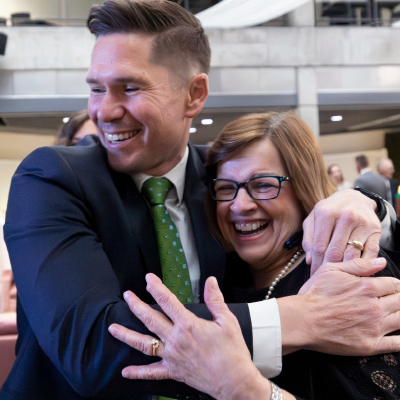 Clark Collings smiles while hugging a woman wearing glasses. 