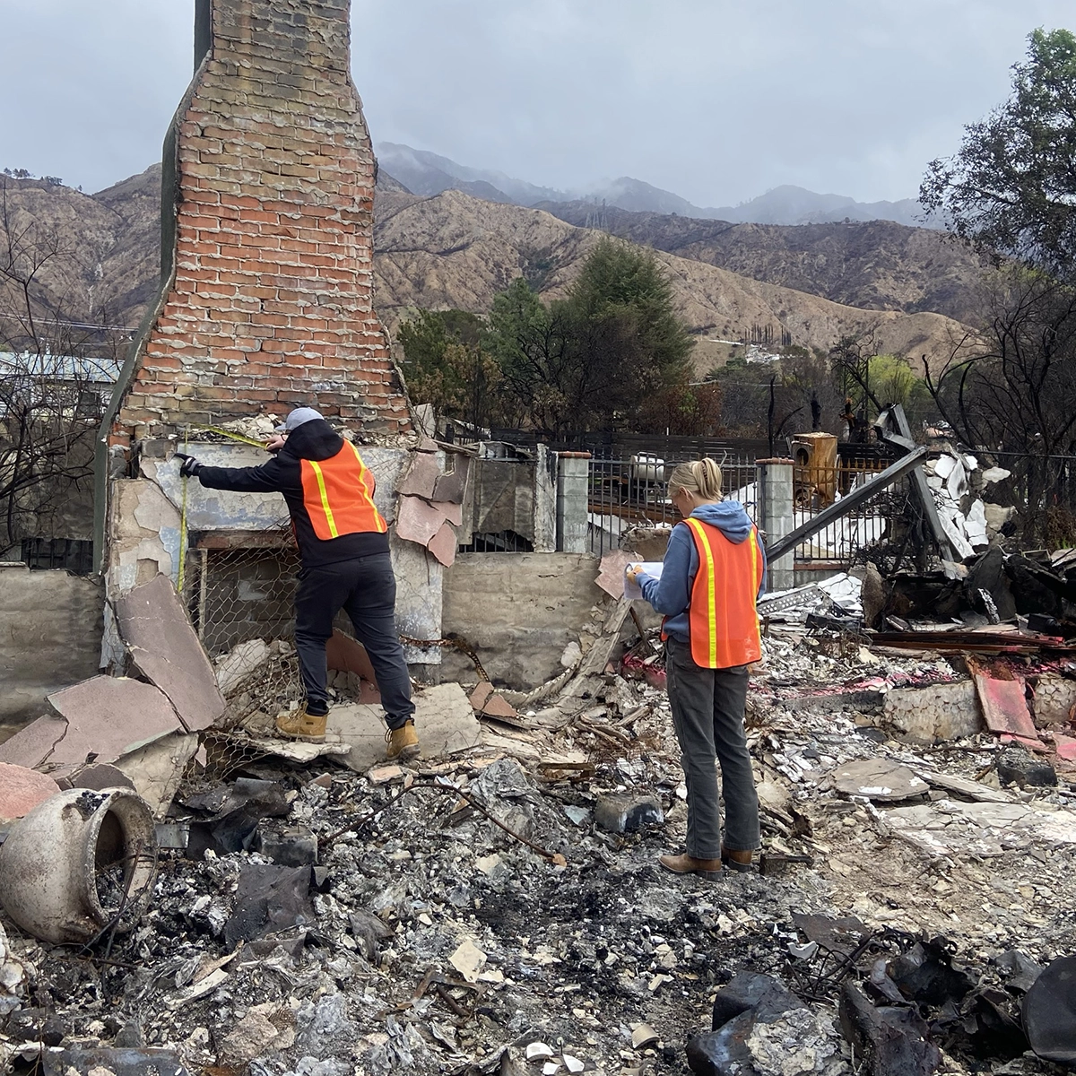 Two UVU architecture students wearing orange construction vests take measurements at the site of a home that burned in the Eaton wildfires in California. Two UVU architecture students wearing orange construction vests take measurements at the site of a home that burned in the Eaton wildfires in California.