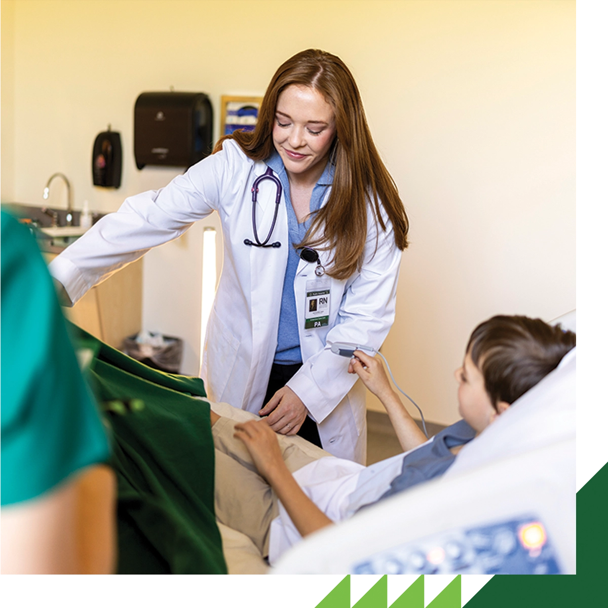 A UVU nursing student wearing a white lab coat cares for a patient in a clinical lab. A UVU nursing student wearing a white lab coat cares for a patient in a clinical lab.