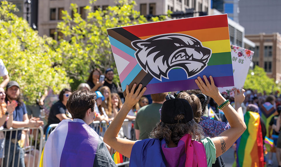 A person holds up the Progress Pride Flag with UVU’s Wolverine logo on it during the Pride Parade in Salt Lake City, Utah, in June 2023. 