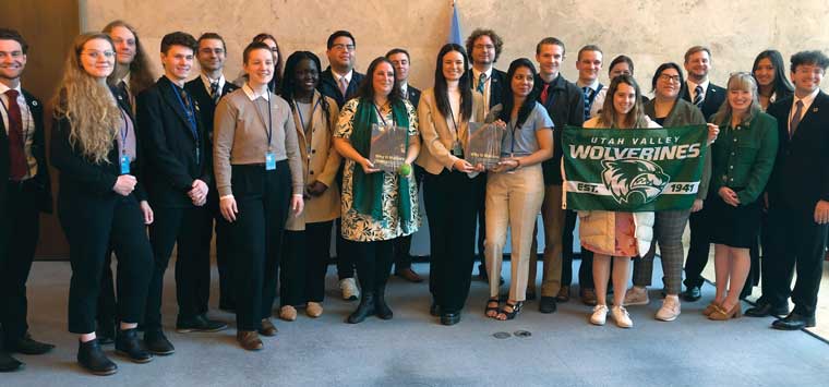 A group of students from UVU’s College of Humanities and Social Sciences pose with a UVU flag and the 1,600-page publication they presented to United Nations officials. 