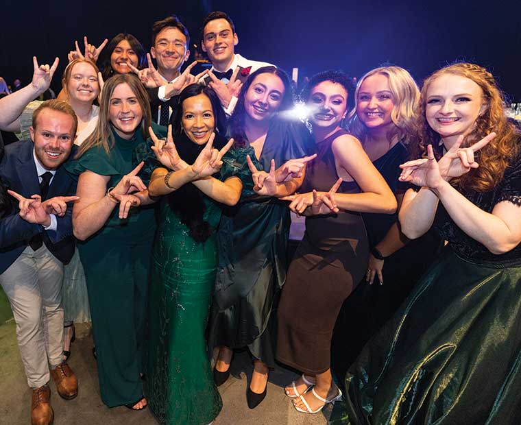UVU President Astrid S. Tuminez and a group of Presidential Interns pose for a photo, making the “Wolverine sign” with their hands. 