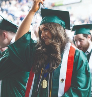 A student wearing green UVU regalia moves the tassel on her cap to the left during UVU’s 2023 commencement ceremony. 