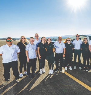 A group of UVU Aviation Program students and faculty pose on a tarmac. 