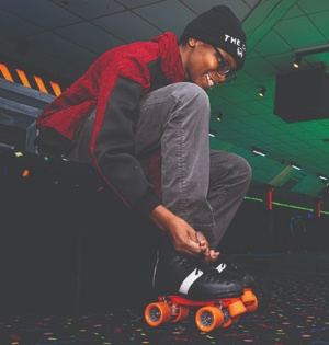 A student puts on roller skates during UVU’s Black History Month skate night event.