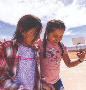 Two young girls from a Navajo Nation elementary school laugh while walking on the grounds of their school. 