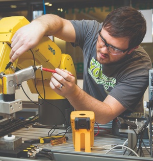A UVU student wears protective goggles as he works on a robotic device. 