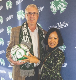 Photo of UVU President Astrid S. Tuminez and UCCU President and CEO Bret VanAusdal with a backdrop of the UVU logo. Together, they are holding a UVU soccer ball, commemorating the announcement of the new UCCU Stadium on UVU’s Orem Campus. 