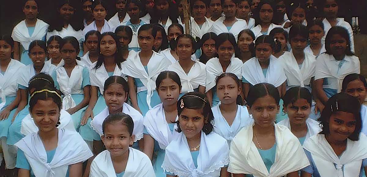 Group photo of young schoolgirls wearing blue dresses and white shawls from a school in Bangladesh, built by UVU professor Abdus Samad. 