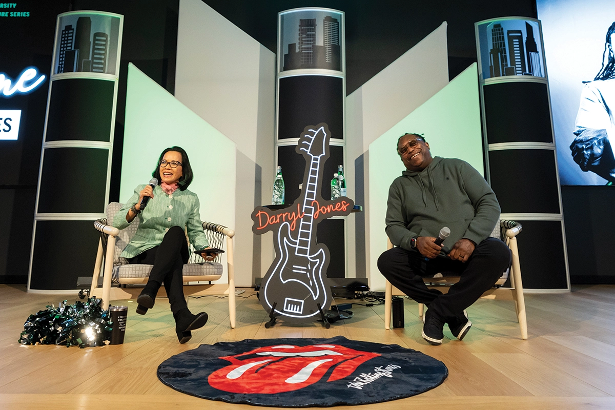 President Tuminez and The Rolling Stones bassist Darryl Jones sit in chairs on a stage during the Presidential Lecture Series. 