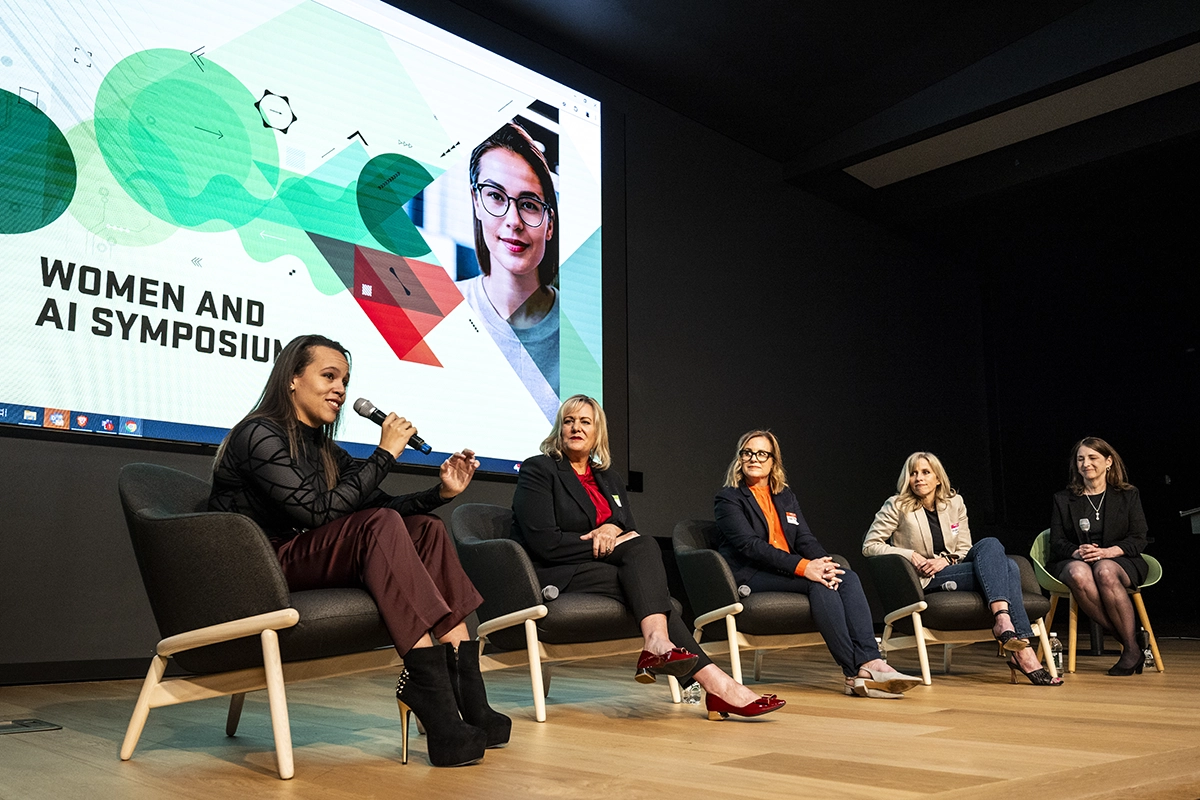 Photo of four people on stage at the Women and AI Symposium on UVU’s Orem Campus. 