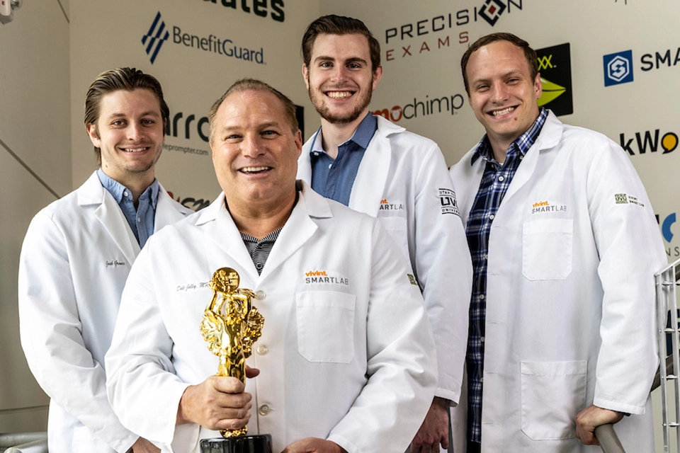 Representatives from UVU’s SMARTLab, wearing white lab coats, smile with a Best of State Award trophy they won.