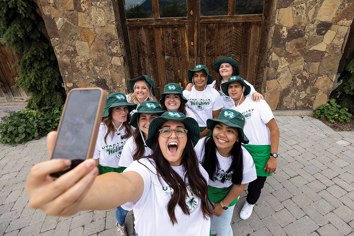 Members of UVU’s Institutional Advancement Strategic Engagement team, wearing white UVU shirts and green UVU bucket hats, pose together for a group selfie. 