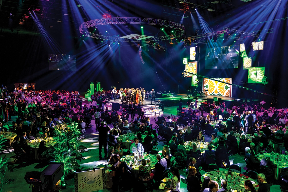 UVU presidential interns and UVU President Astrid S. Tuminez dance on stage at the 2023 President’s Scholarship Ball in front of a large audience. 