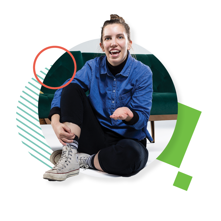 UVU student Kaitlin LeBeau, wearing a blue shirt, black pants, and white Converse sneakers, sits on the floor next to a green couch.