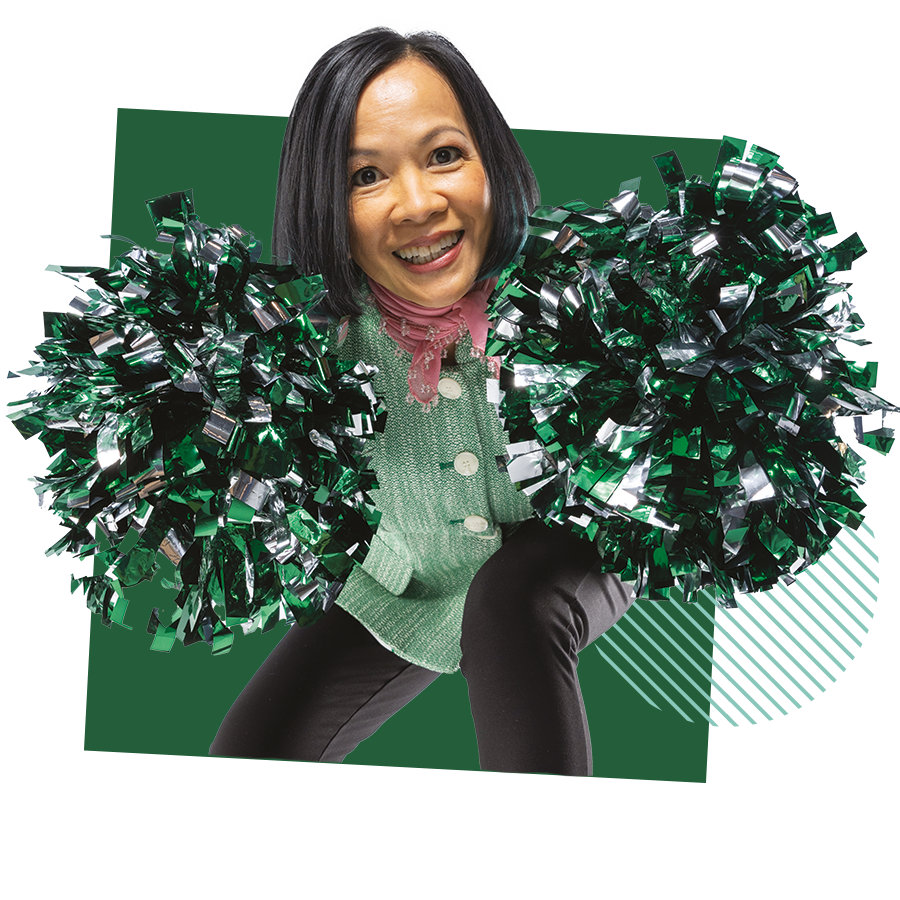 President Tuminez smiles while posing with green and silver pom-poms.