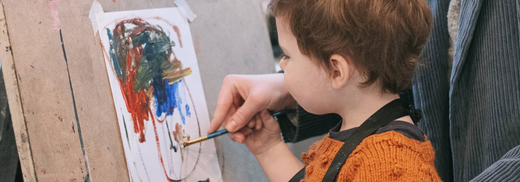 Young boy painting on canvas