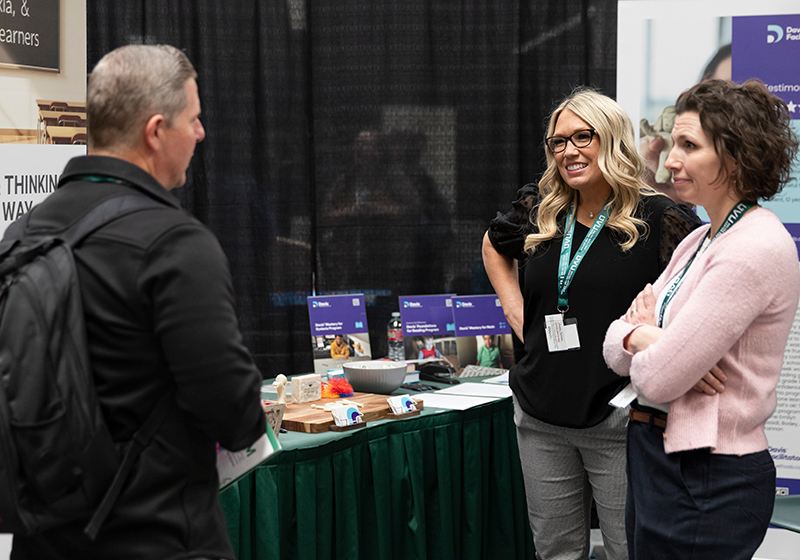 Image of attendees talking by a booth.