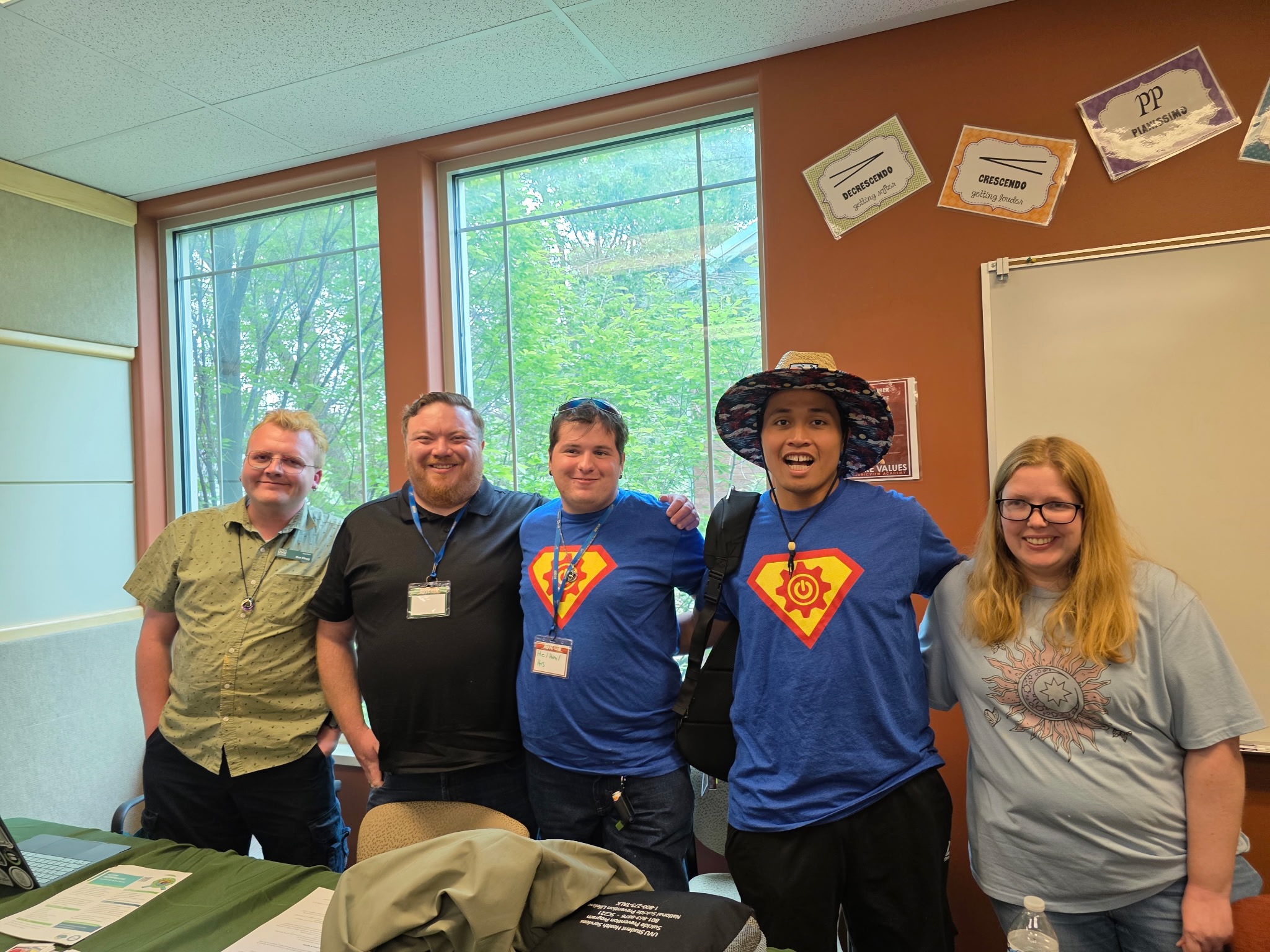 5 people lined up posing for a picture in a classroom