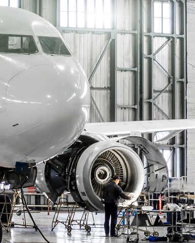 maintenance tech standing at turbofan engine