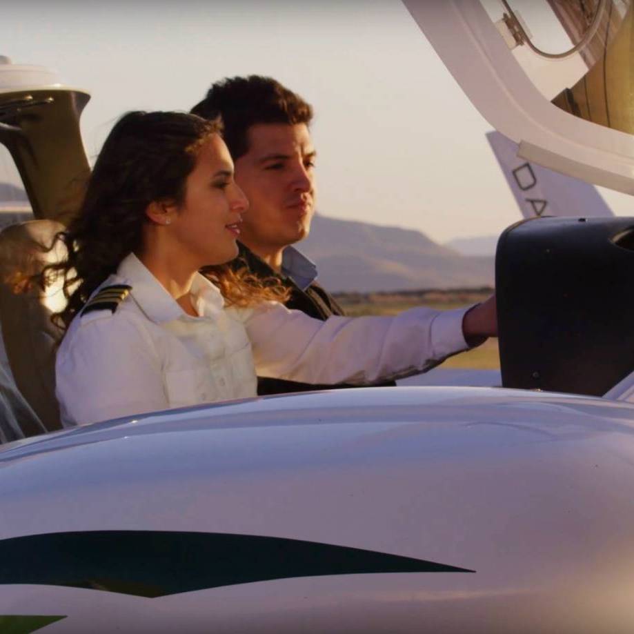 Female Pilot teaching male student in the cockpit of a small aircraft on the ground