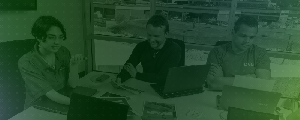 three students working in a campus boardroom