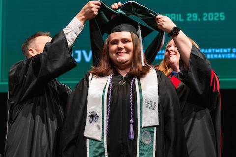 gradudate being hooded by faculty during ceremony