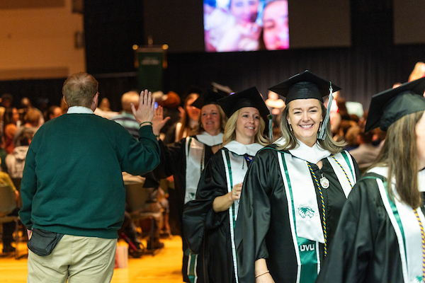 man high fiving graduats as they exit ceremony