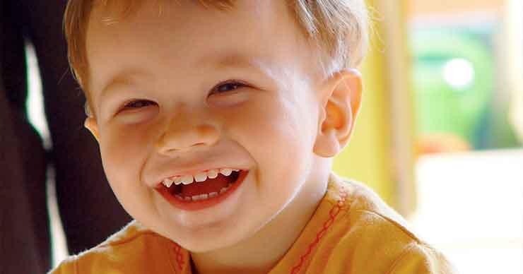 A toddler boy smiling and laughing. 