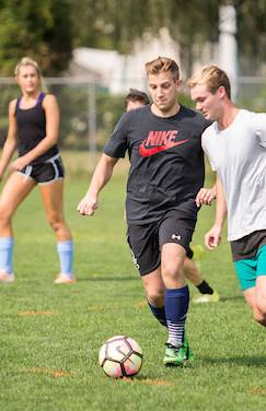 Two men playing soccer with two woman behind them also playing soccer