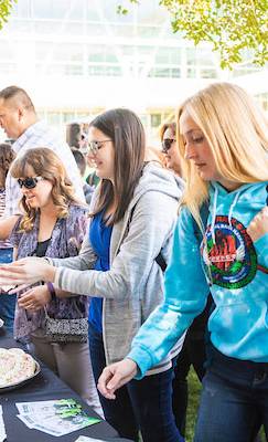 Students picking up food from a table on UVU campus