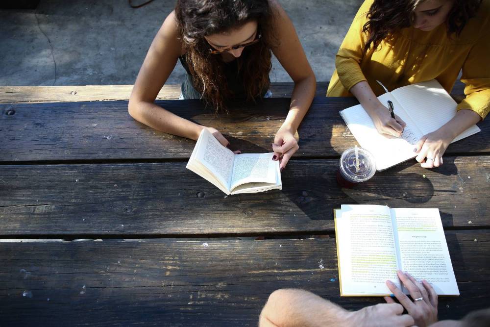 Image of students reading at a table outdoors